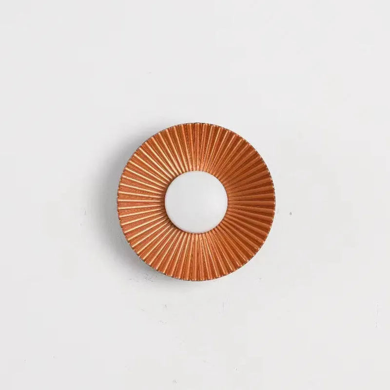 A round, modern wall lamp with an aluminium shade, shown in a two-tone gold and white finish, mounted on a wall.