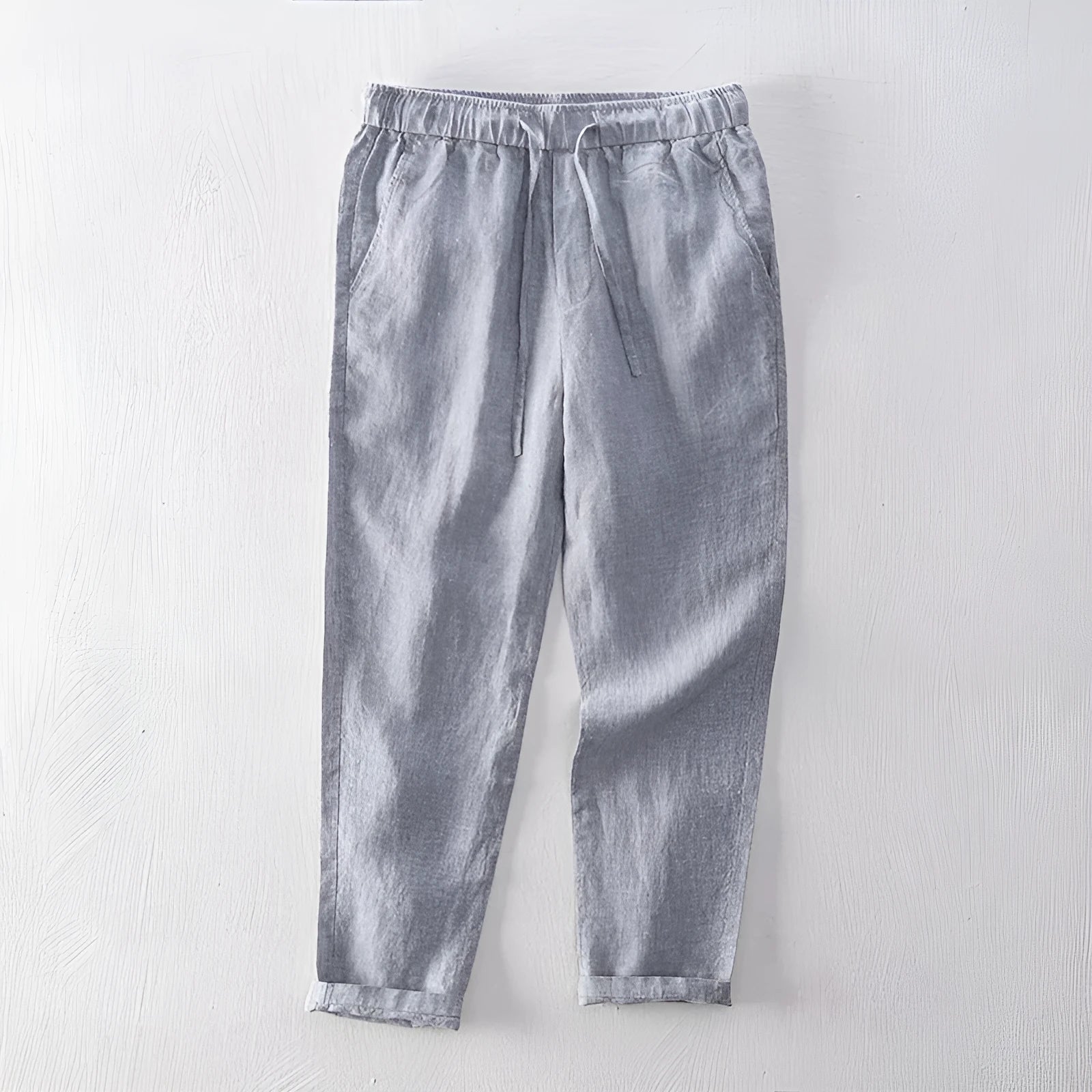 Men's straight leg linen trousers in dark grey, shown laid flat.