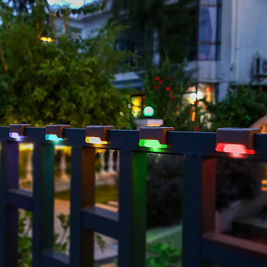 Set of four brown solar step lights with warm LED glow mounted on outdoor wooden stairs