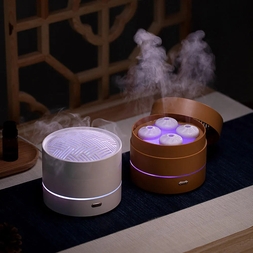 White ultrasonic aroma diffuser with four steam nozzles and LED light on a wooden table