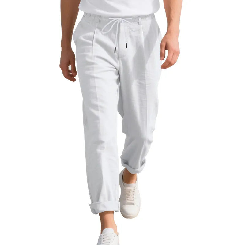 Men's light beige linen trousers with drawstring waist and straight-leg design laid flat