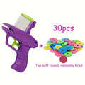 Green durable plastic manual cat toy launcher with a stack of soft foam discs on a floor.
