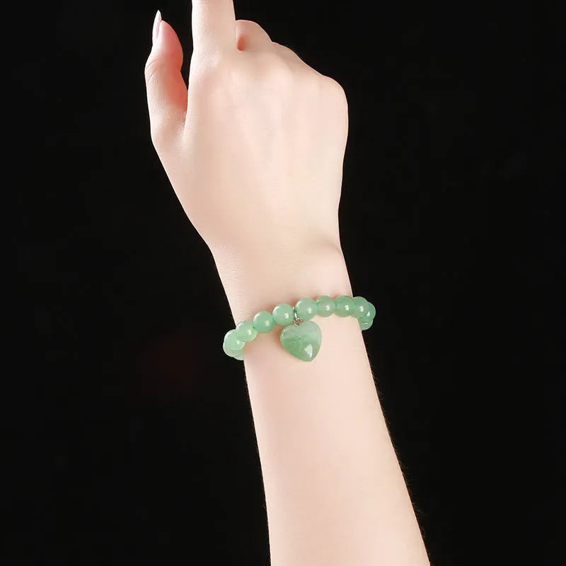 Natural stone love heart pendant bracelet on wrist, showing Tigereye, crystal or aventurine beads.