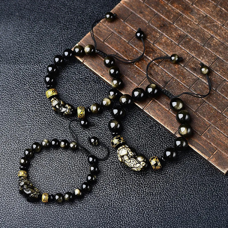 Golden obsidian bead Pi Xiu bracelet with hand-woven design on a wrist.