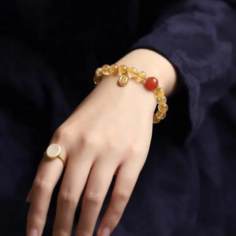 Red agate natural stone bracelet with gold and ruby accent beads on a wrist.