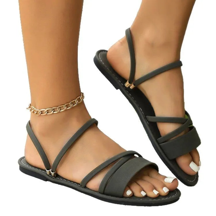 Women's flat cross-strap sandals with buckle closure in black, brown or green colours