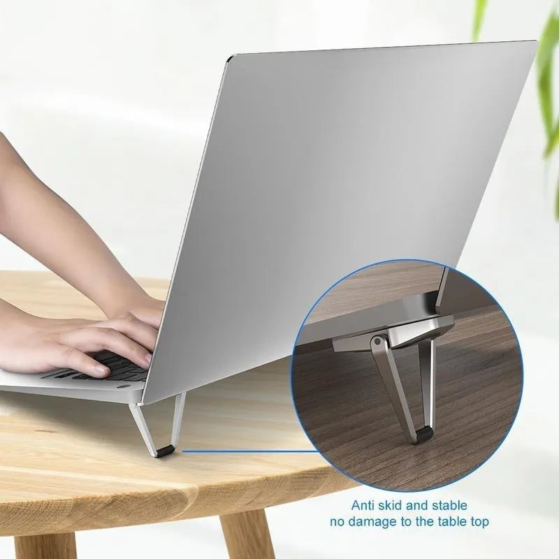 Small foldable aluminium laptop stand in silver colour next to laptop for size comparison