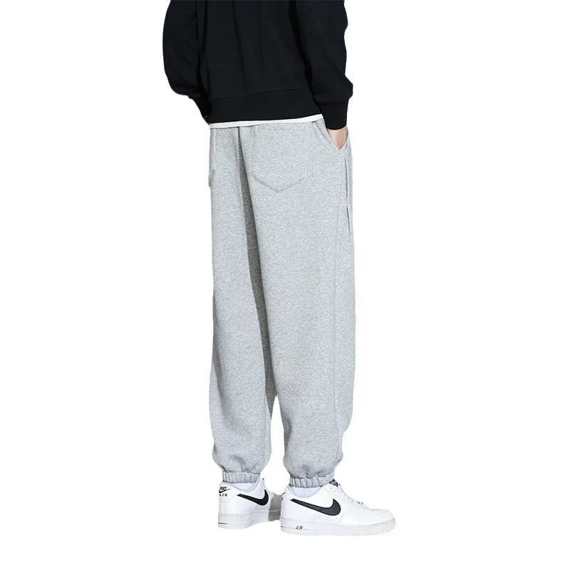 Men's loose grey cotton blend sports trousers with drawstring waist on a hanger.