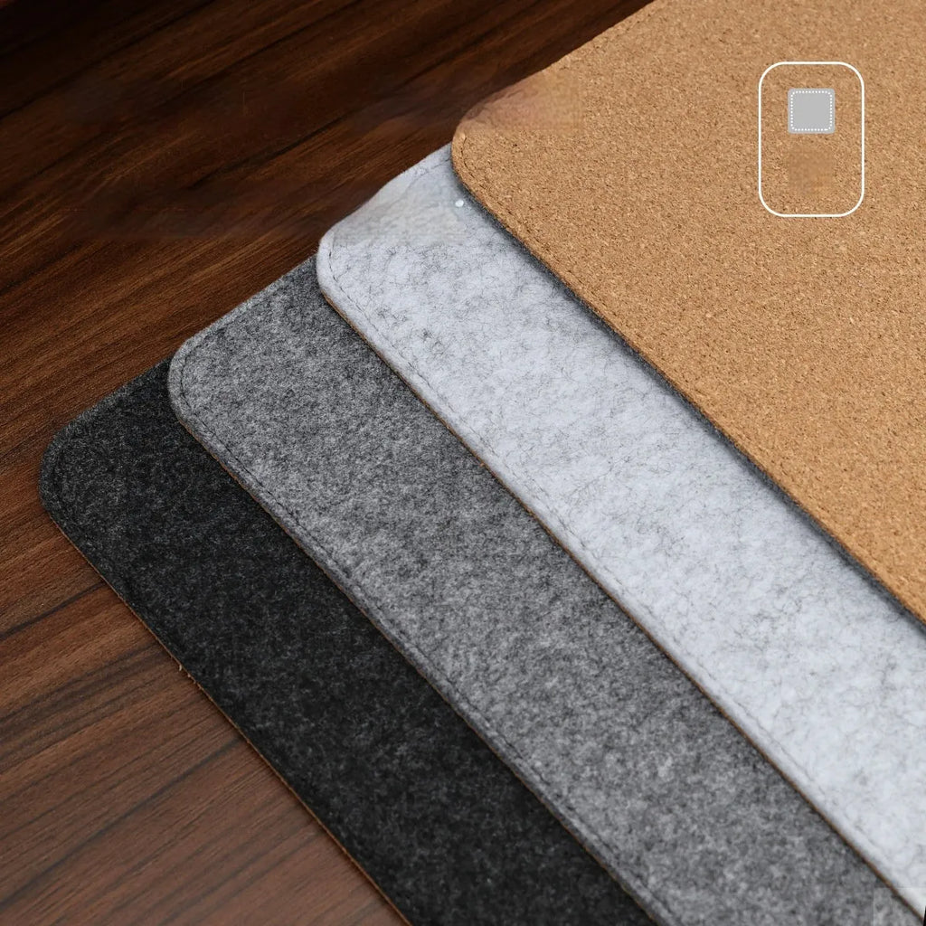 A grey and black felt cork desk mat with a mouse on it, shown on a wooden desk.