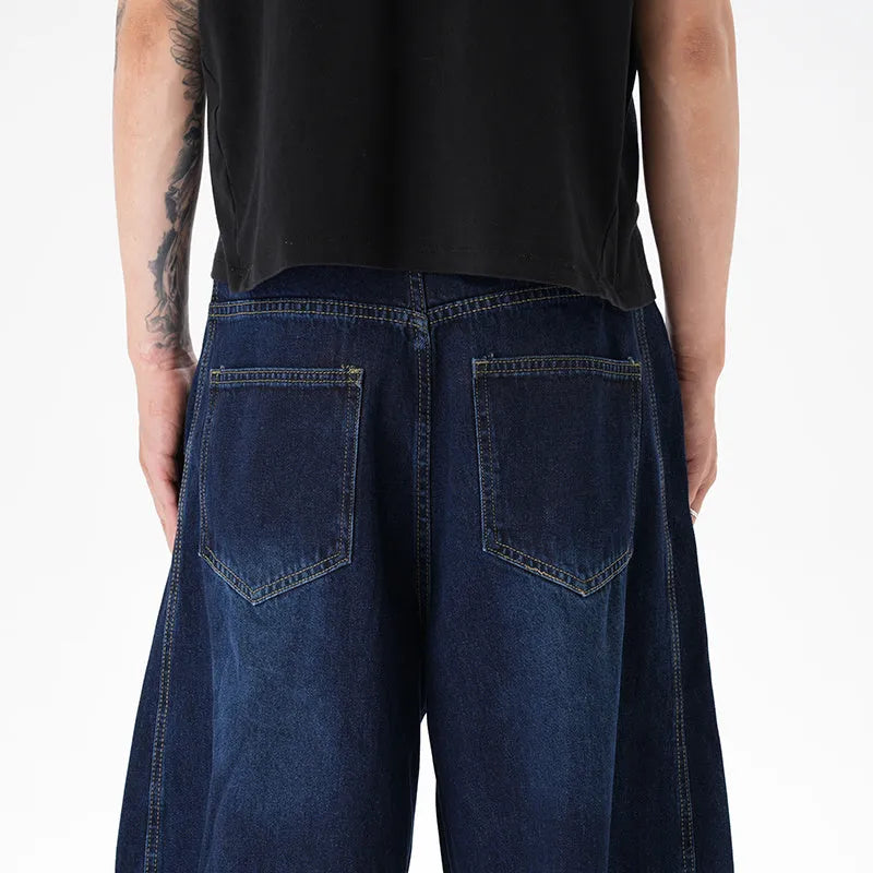 Dark blue wide leg distressed jeans on a hanger showing washed denim fabric and machete cut.