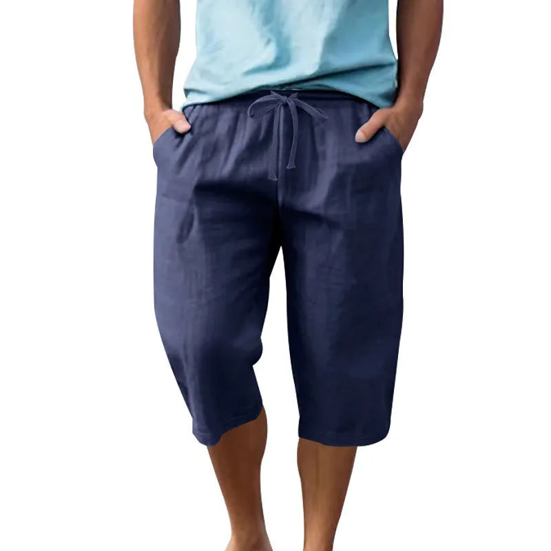 Men's loose linen shorts in light blue with drawstring waist and cropped length on white background
