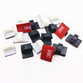 Black and white self-adhesive plastic clamps for organising car wiring cables.