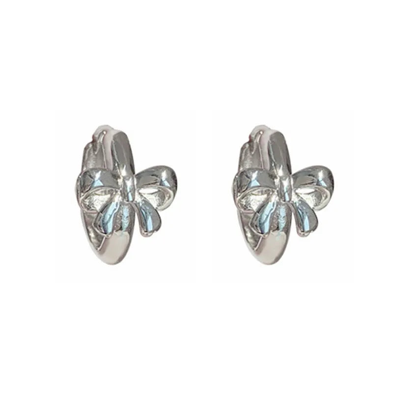 A pair of 925 sterling silver bow earrings in silver colour with electroplating finish on a plain background