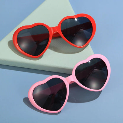 Heart-shaped glow-in-the-dark sunglasses in various vibrant colors, featuring a durable plastic frame and resin lenses for reliable UV protection.