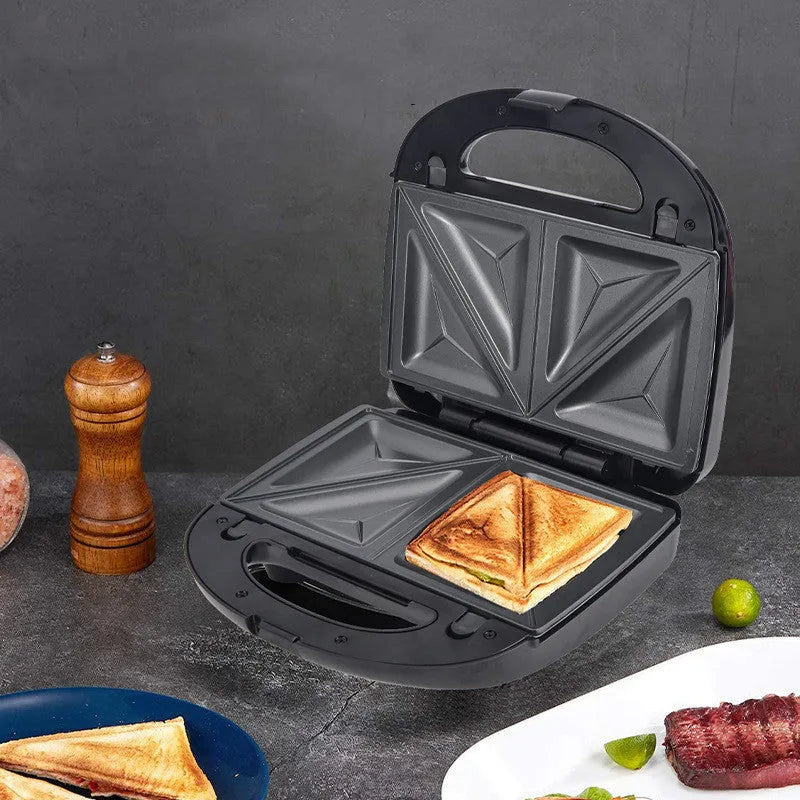 Black double-sided electric sandwich pan with brushed stainless steel lid on kitchen counter