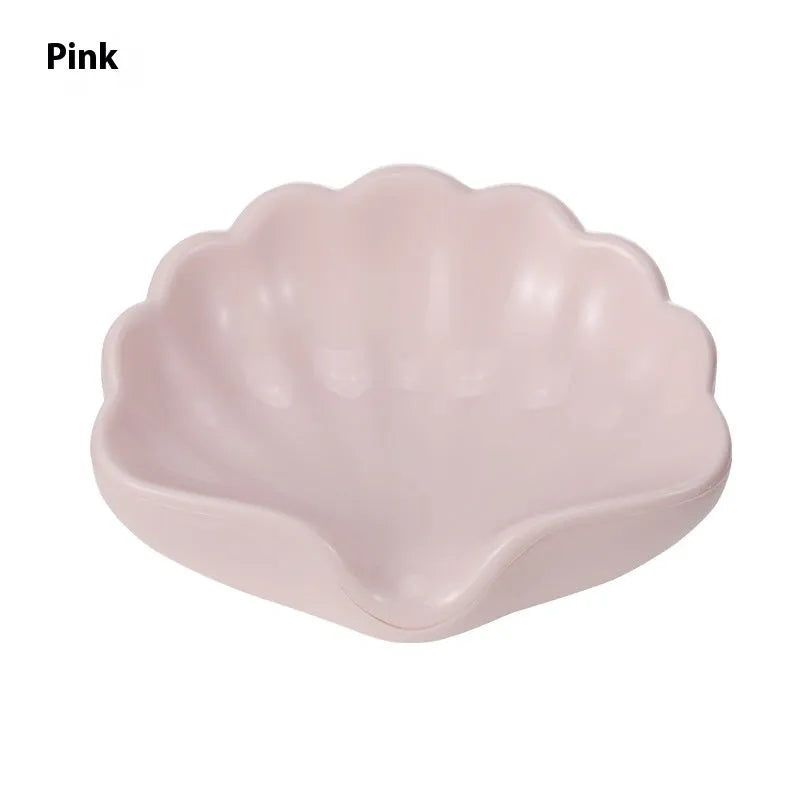 White shell-shaped plastic soap dish with drainage holes on a bathroom surface