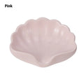 White shell-shaped plastic soap dish with drainage holes on a bathroom surface