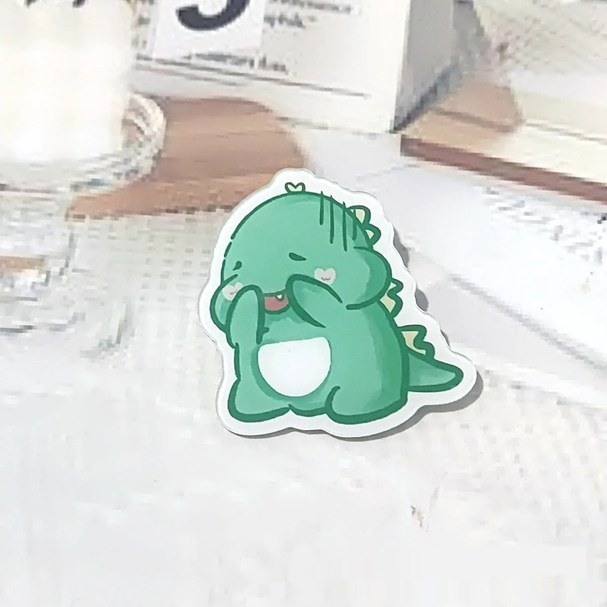 Cartoon dinosaur acrylic badge brooch with printed design and pin fastening, shown in one of twelve colour styles