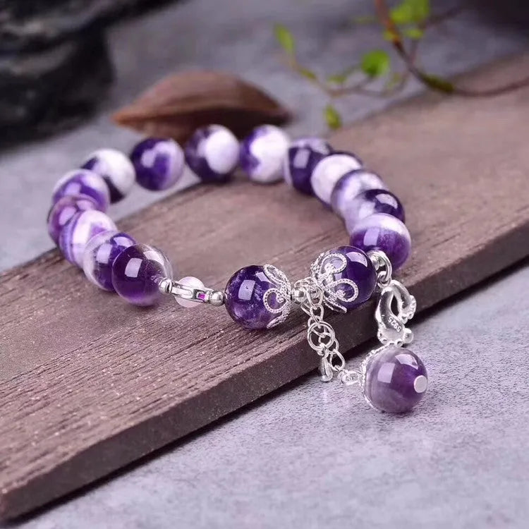Natural amethyst bracelet with 10mm round beads on a woman's wrist.