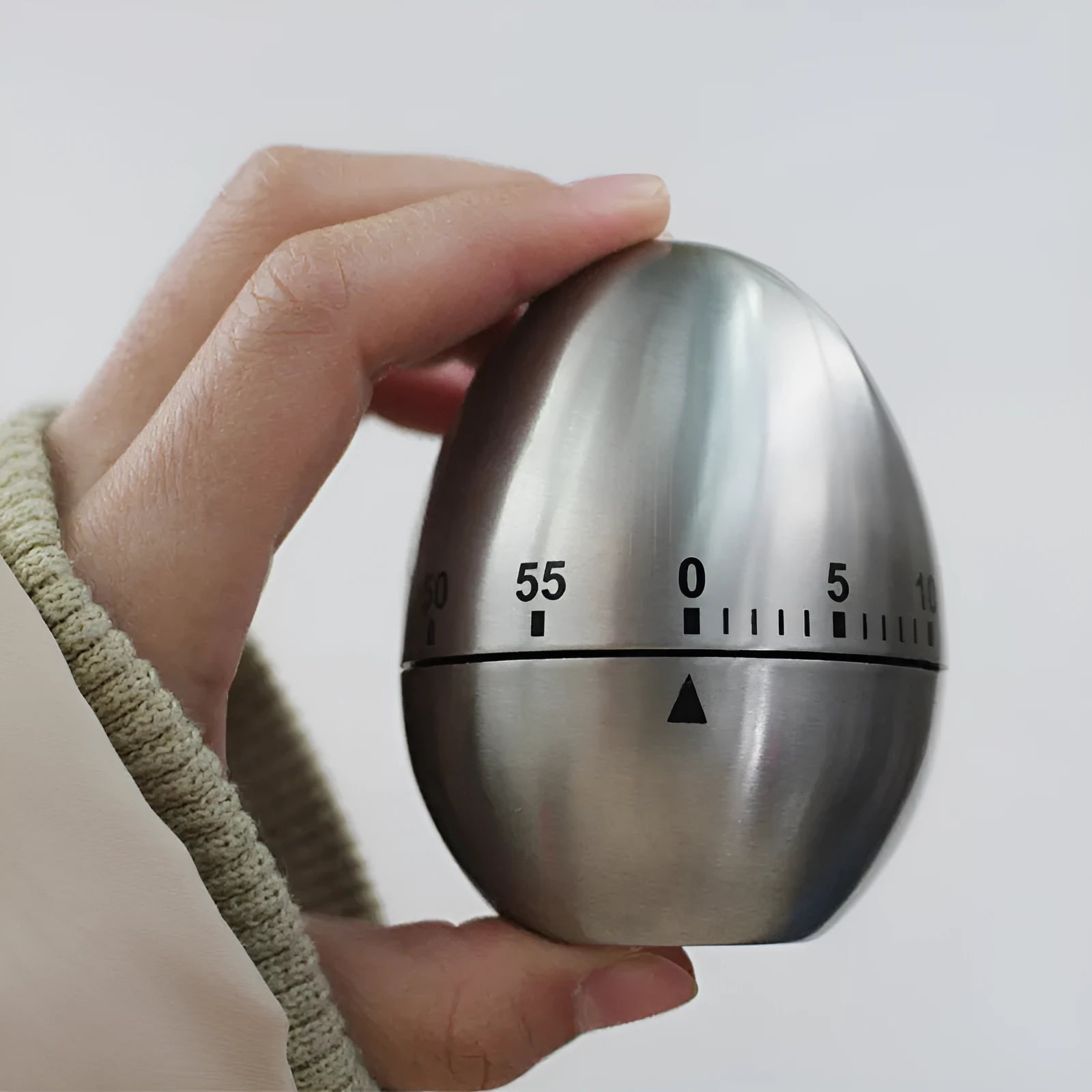 Stainless steel egg-shaped mechanical kitchen timer on a kitchen counter