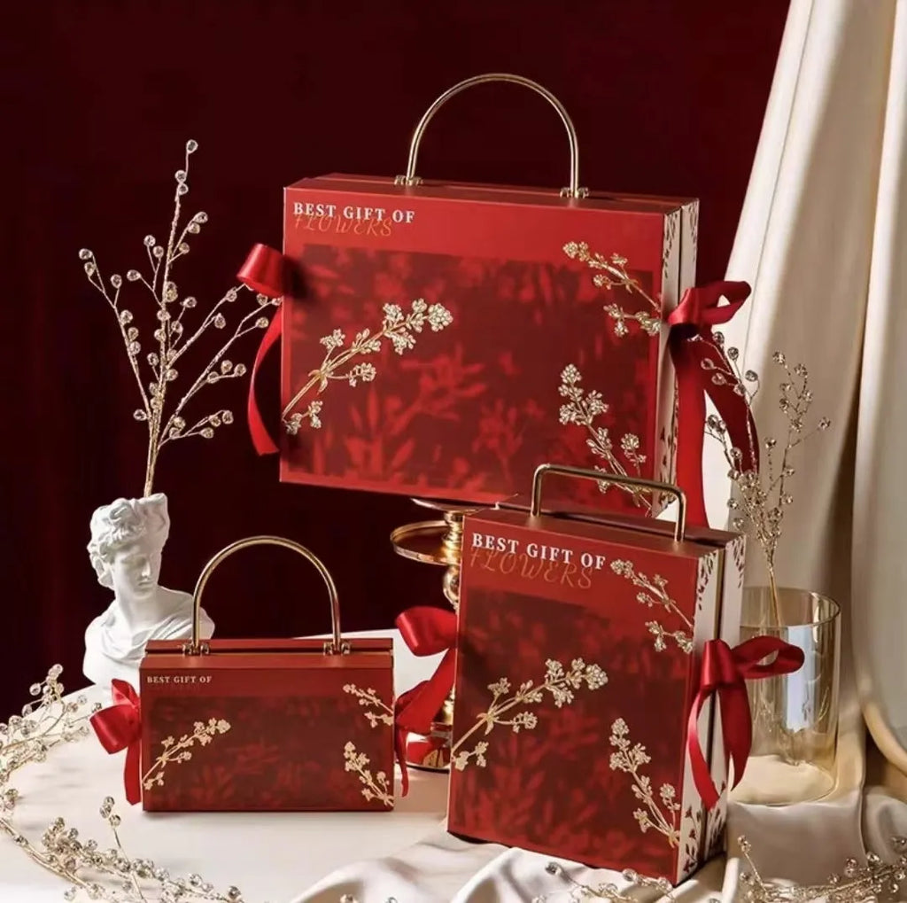 Hand gift box in paper and cardboard, champagne gold, glacier blue or red, with string lights, raffia or single box options.
