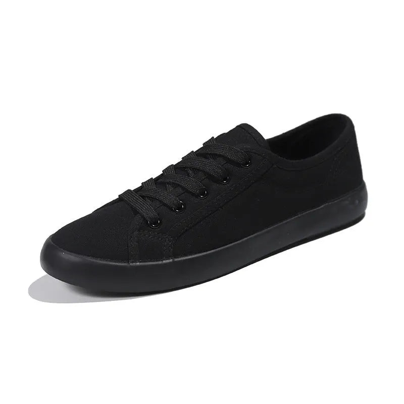 All-black women's canvas flat shoes with lace-up front and rubber soles.