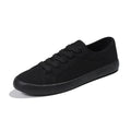 All-black women's canvas flat shoes with lace-up front and rubber soles.