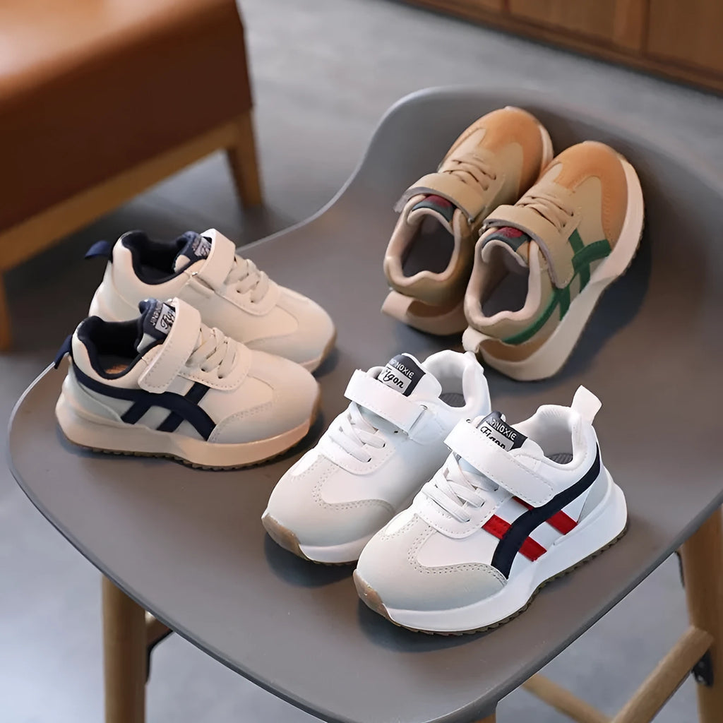 Children's white synthetic leather sneakers with Velcro fastening and textured rubber sole.