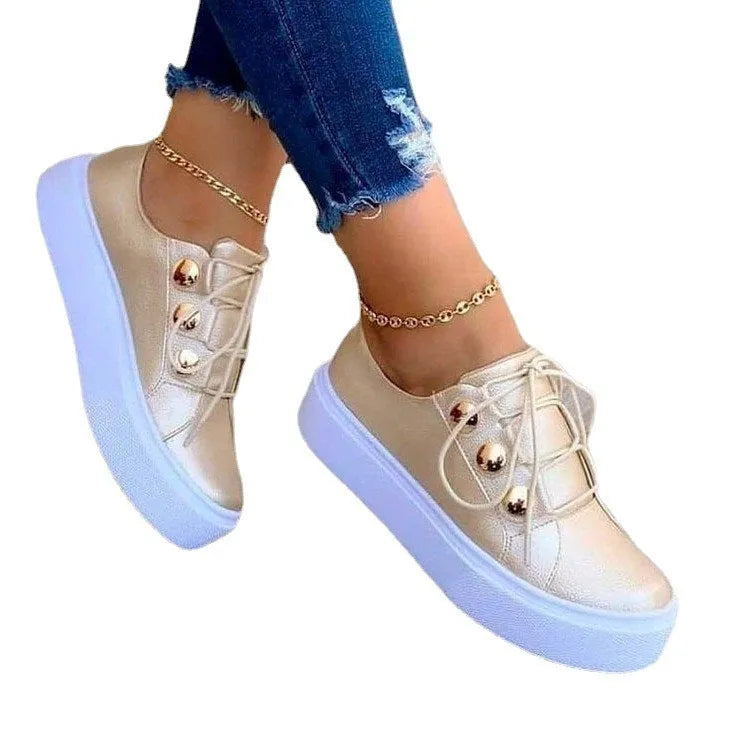 Women's white lace-up flats sneakers with round toe and metallic rivet detailing on a low upper.