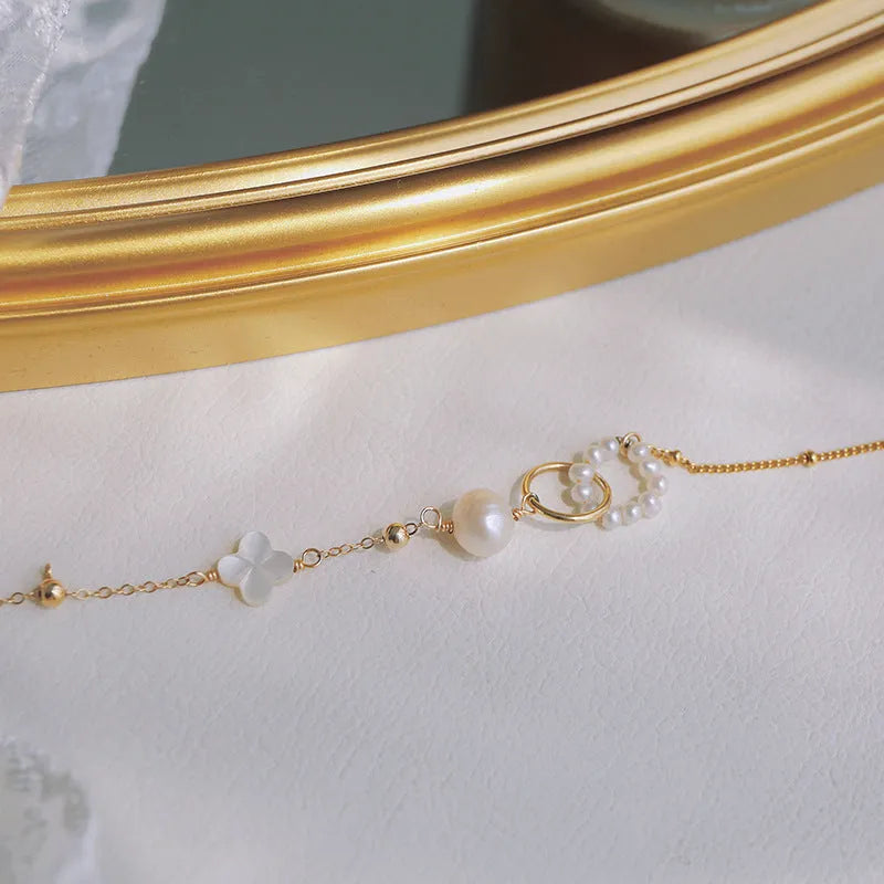Women's natural pearl and gold-plated chain bracelet on a white background.
