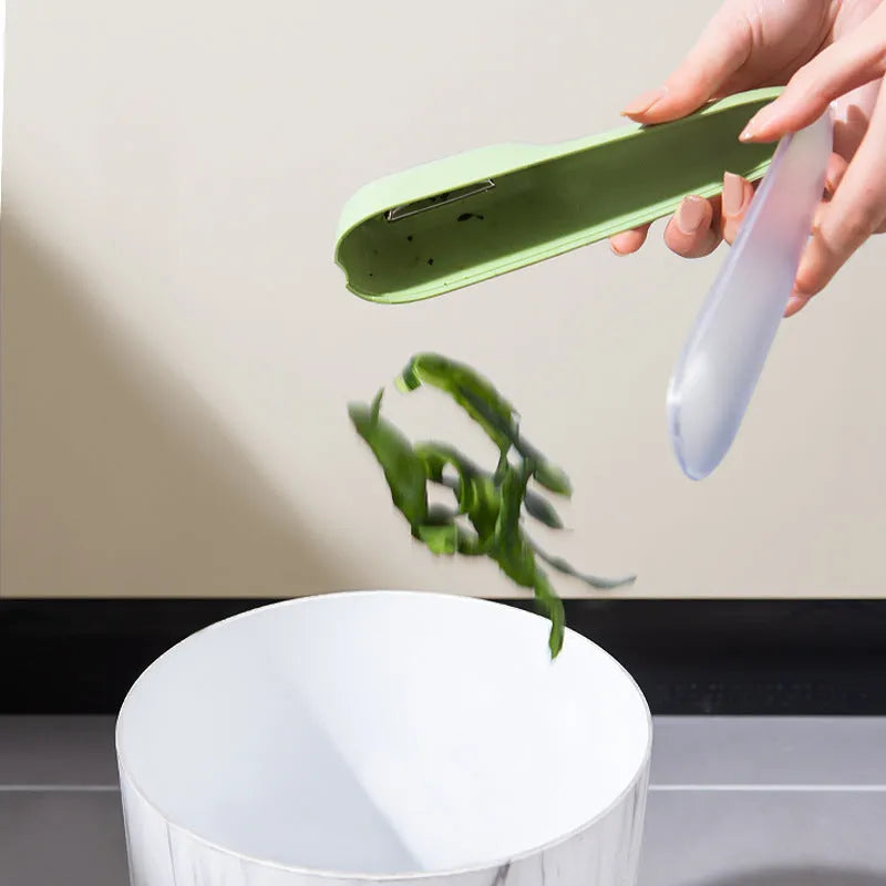 Dark green kitchen peeler with stainless steel blade stored in transparent tube case