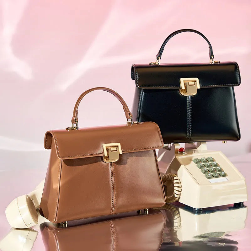 Women's black genuine leather shoulder bag with vachette clasp closure showing internal compartments