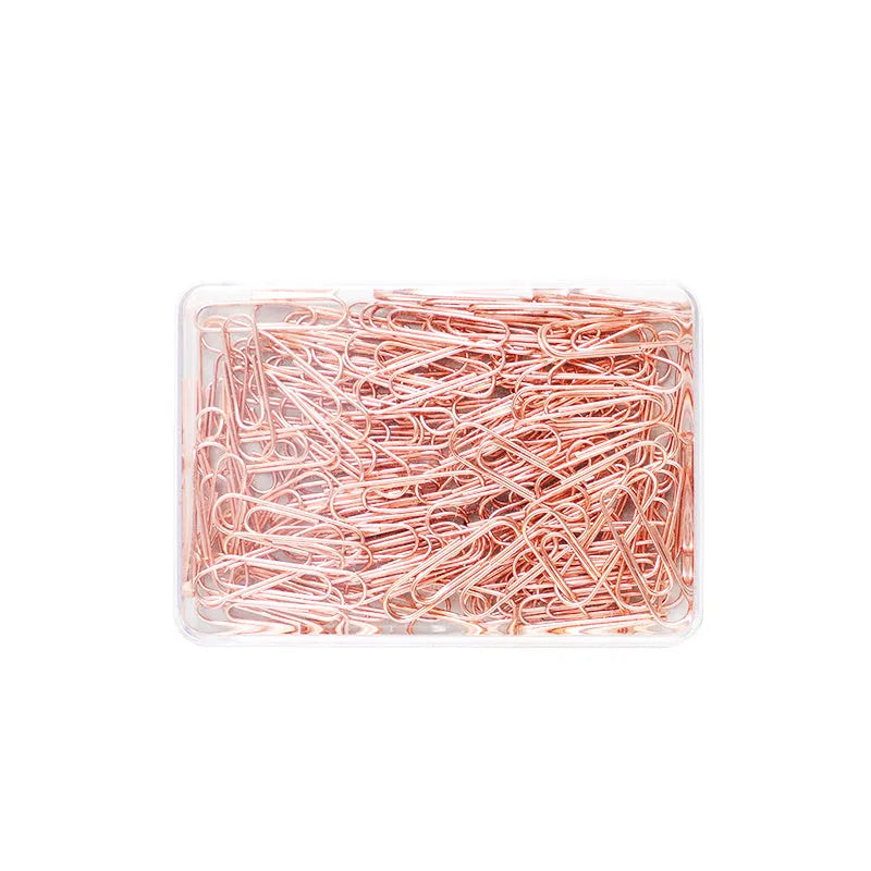 Box of 100 small rose gold heart-shaped metal paper clips on a white surface.