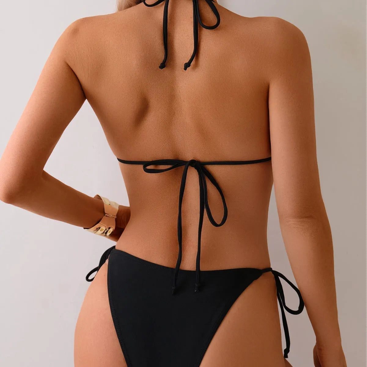 Black women's bikini swimsuit with metal bead detail and split design.