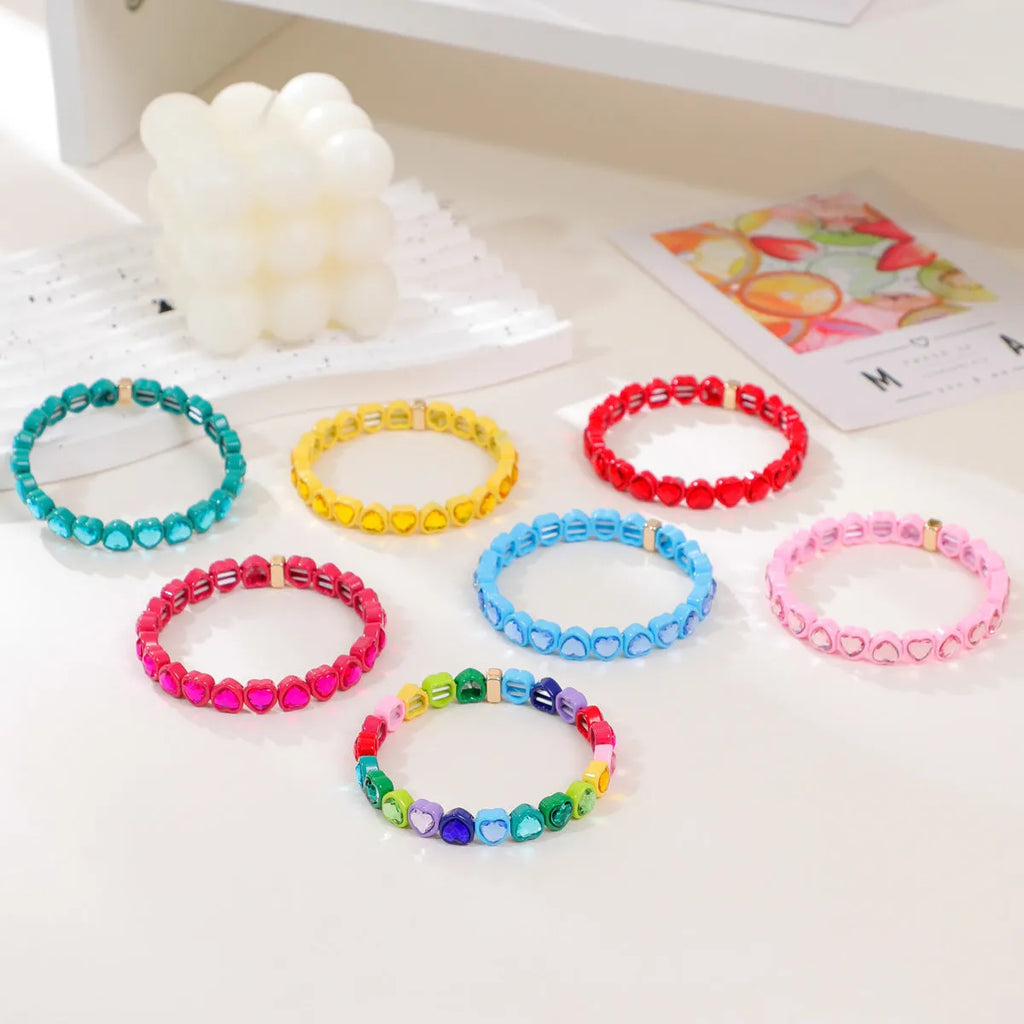 Rainbow enamel heart pendant on a stretch alloy bracelet, shown in multiple colour options.