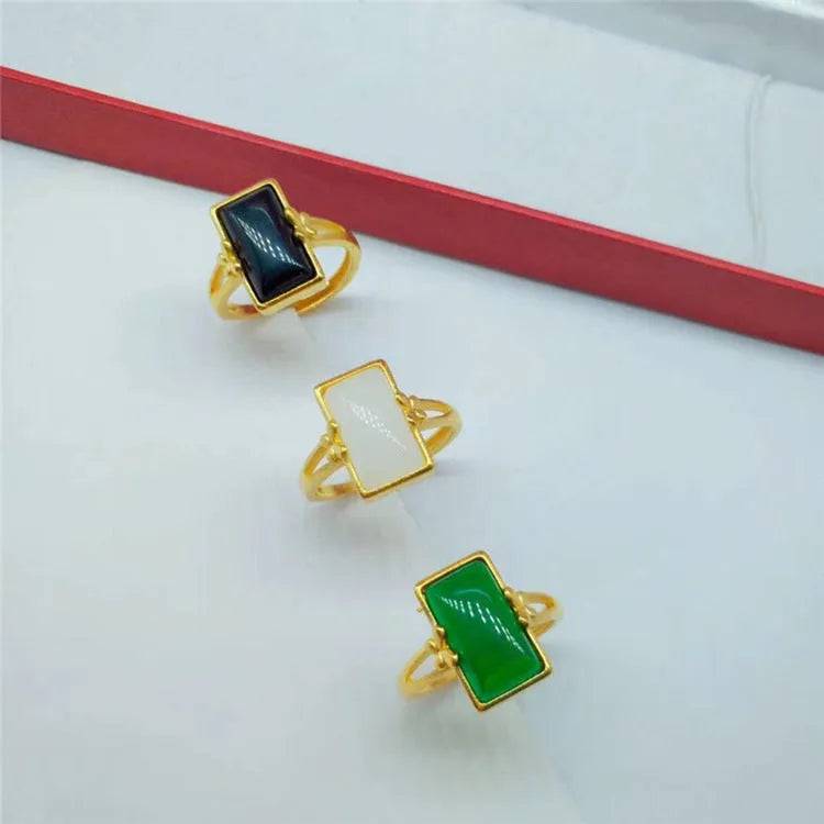 Adjustable brass gold-plated ring with a central green gemstone inlay on a finger.