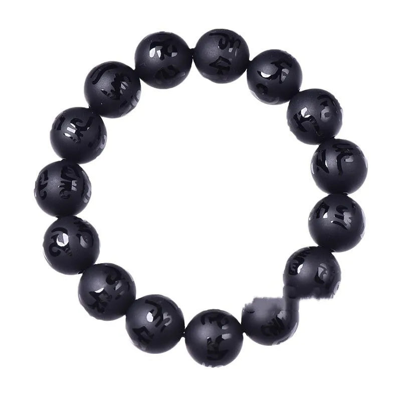Close-up of a frosted black agate bracelet with an engraved Sanskrit mantra, showing stone texture.