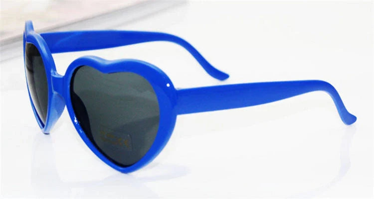 Heart-shaped glow-in-the-dark sunglasses in various vibrant colors, featuring a durable plastic frame and resin lenses for reliable UV protection.