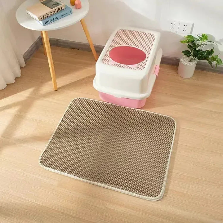 Black waterproof EVA cat litter mat with honeycomb texture and quilted edge on a wooden floor