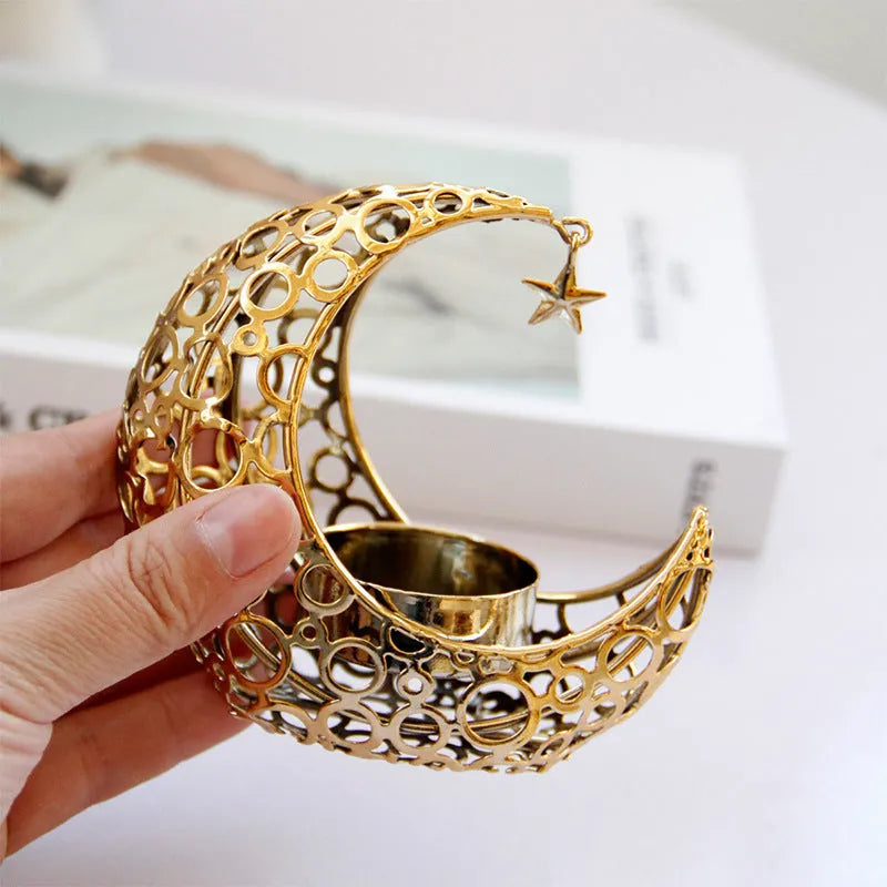 Black metal crescent moon candle holder with star cutouts on a table