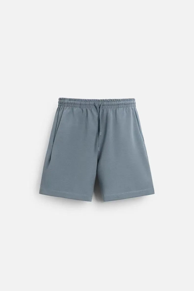 Loose-fitting white short sleeve top and matching shorts set on a hanger, showing round collar and cloth texture.