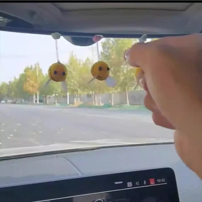 Small black and yellow cartoon bee car decoration with a spring, on a fur ball.