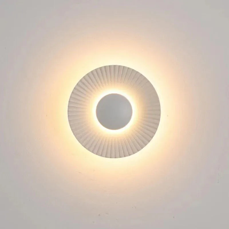 A round, modern wall lamp with an aluminium shade, shown in a two-tone gold and white finish, mounted on a wall.