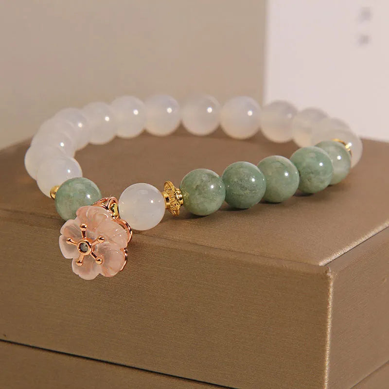 Women's white agate jade bracelet with flower design and pink accents on adjustable sliding knot closure