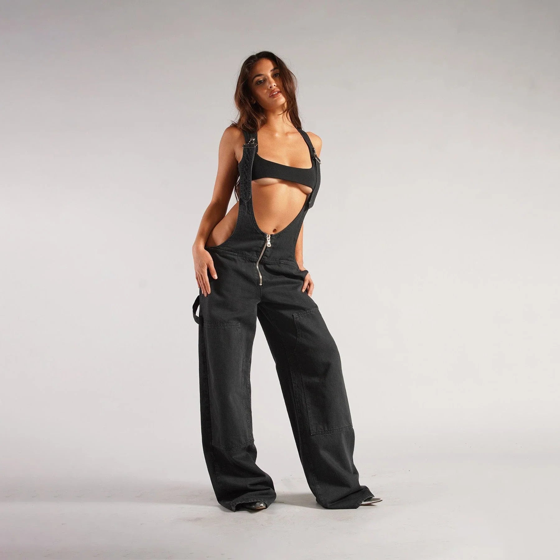 Stylish Y2K-inspired denim suspender jumpsuit with pockets, featuring a relaxed wide-leg silhouette and adjustable straps for a customized fit.