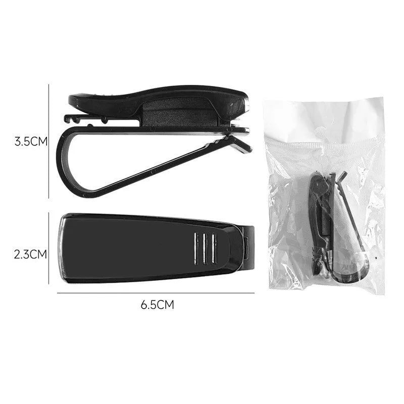 Black plastic clip for car sunshade holding sunglasses and a ticket.