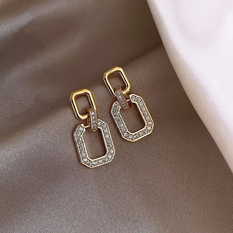 Pair of geometric alloy ear studs with electroplated finish on white background