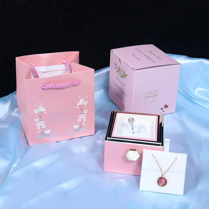 Rotating jewellery box with preserved red rose under acrylic cover and drawer open showing storage