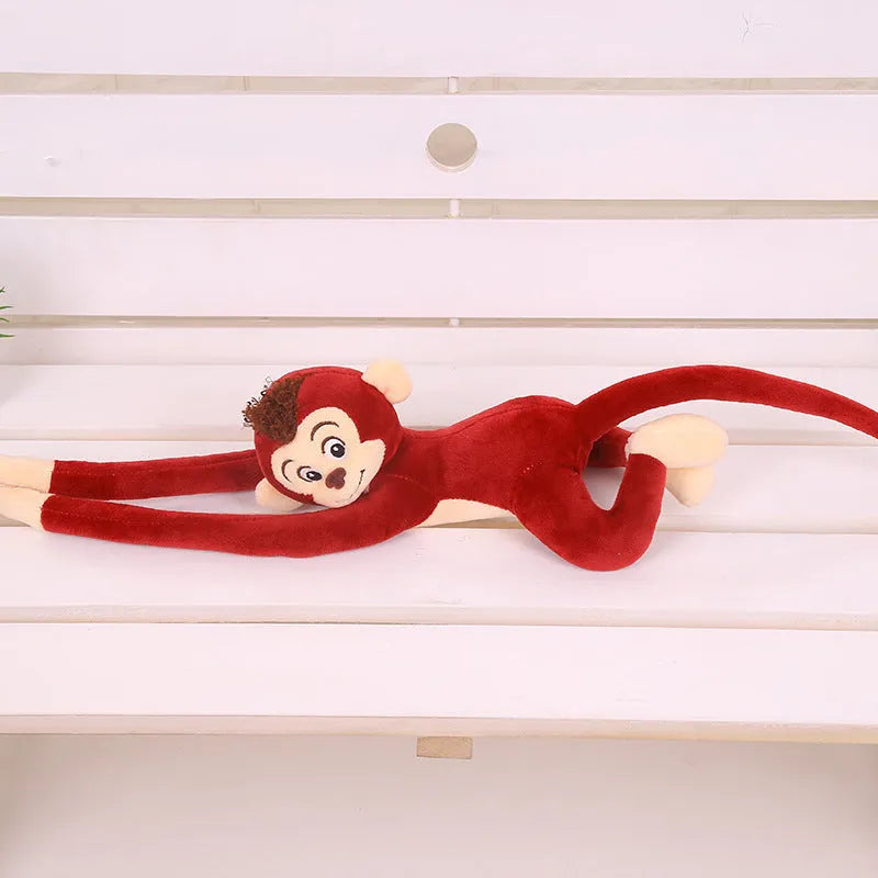 Long arm hanging monkey plush toy decoration in pink colour draped over curtain pole