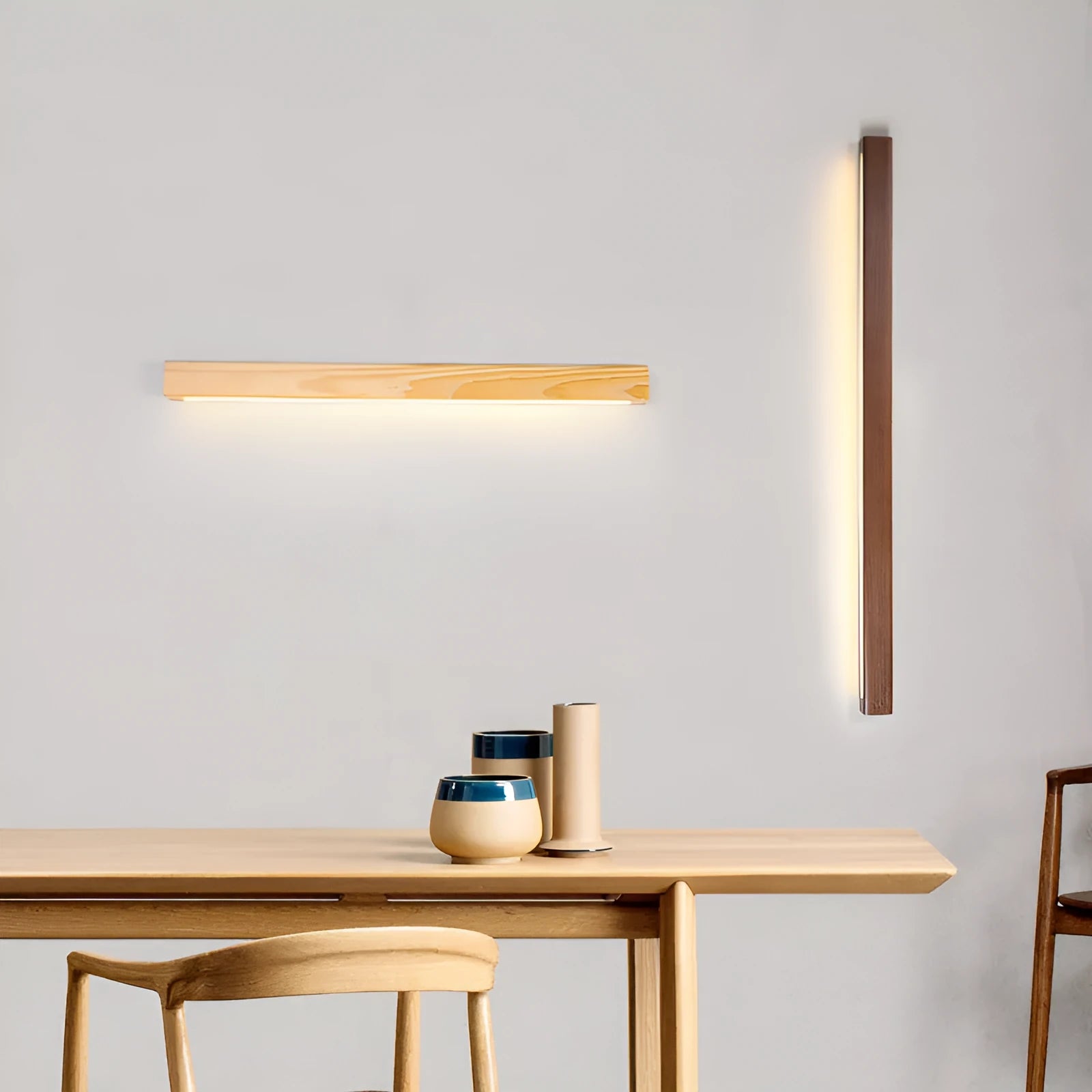 Long, slim walnut-coloured wooden wall lamp with integrated LED lighting on a plain wall.